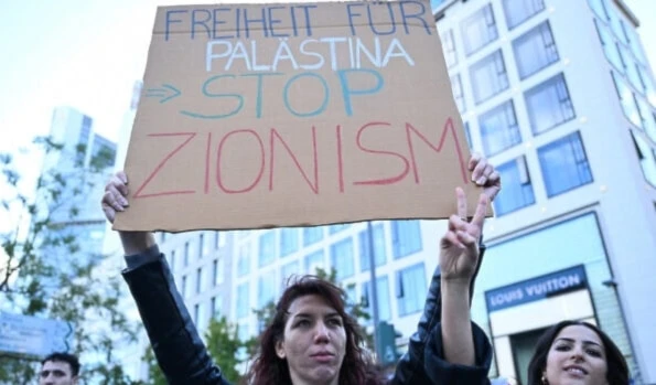 A protester displays a placard calling for the end of Zionism during a pro-Palestinian rally in Frankfurt, Germany on October 14, 2023, amid the ongoing genocide in Gaza. (AFP)