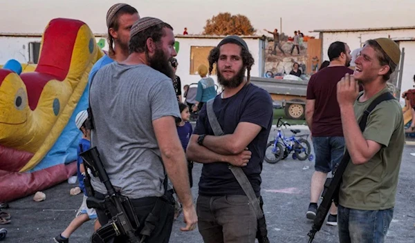 Israeli settlers with assault rifles in the West Bank on 1 July 2021 (AFP)