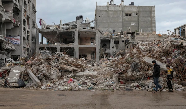 Palestinians walk by a destroyed building in Jebaliya refugee camp, Gaza Strip, Tuesday, Nov. 28, 2023. (AP Photo/Mohammed Hajjar)