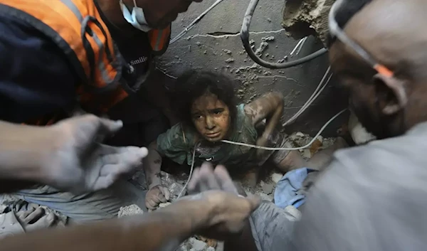 Palestinians try to pull a girl out of the rubble of a building that was destroyed by Israeli air strikes in Jabaliya refugee camp, on 1 November 2023 (AP)