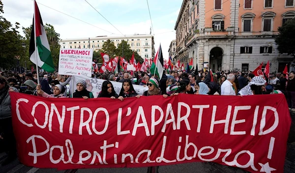 Demonstrators show a banner reading in Italian "against apartheid, Free Palestine" during a rally in support of the Palestinian population in Gaza, in Rome, Saturday, Nov. 4, 2023. (AP Photo/Alessandra Tarantino)