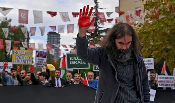 A man raises his hand painted in red during a pro Palestinians protest outside Turkish Foreign Affairs Ministry in Ankara, Turkey, Monday, Nov. 6, 2023. (AP)