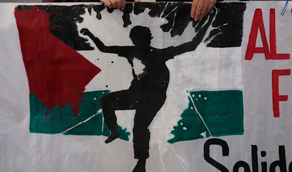 A protester takes part in a demonstration march carrying a banner showing the Palestinian flag, in support of Palestinians in Madrid, Spain, Saturday, Dec. 2, 2023 (AP Photo/Paul White)