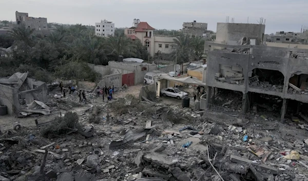 Palestinians look at buildings destroyed in the Israeli bombardment of Al Zawayda, central Gaza Strip, on Sunday, Dec. 10, 2023. (AP Photo/Hatem Moussa)