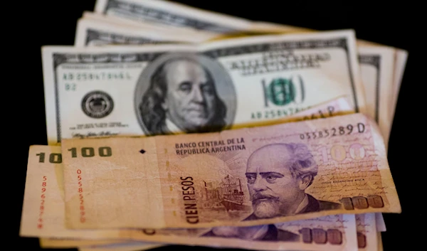 U.S. dollar bills and Argentine pesos are displayed for the photographer on a table at a currency exchange business in Buenos Aires, Argentina, Thursday, Jan. 23, 2014. (AP)