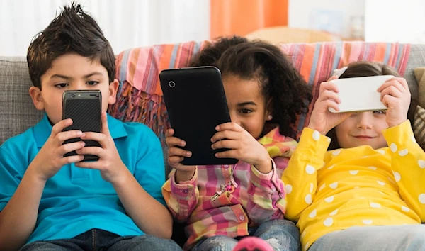 Children are seen holding cell phones in an undated image (Getty via AFP)