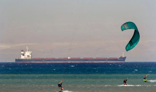 Egyptian holiday-makers play water ski as a cargo container ship, crosses the Gulf of Suez towards the Red Sea at al Sokhna beach in Suez, 127 kilometers (79 miles) east of Cairo, Egypt, Friday, Aug. 26, 2022