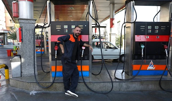 A worker leans against a gasoline pump that has been turned off, at a gas station in Tehran, Iran, Tuesday, Oct. 26, 2021 (AP)