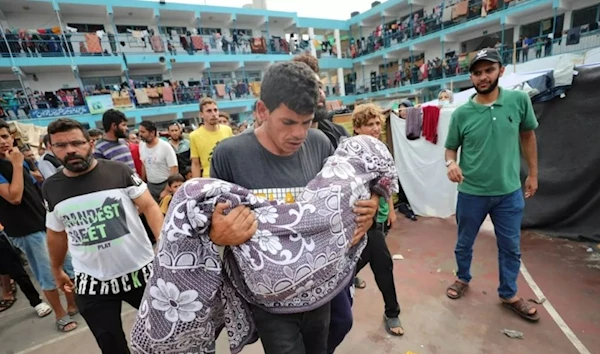 Palestinian father carries his child in the Israeli bombardment of the Gaza Strip during his funeral at a UN-run school in Deir al Balah, Gaza Strip, 27 October 2023 (AP)