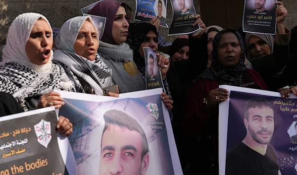 Palestinian women hold posters of Nasser Abu Hamid, a veteran Palestinian prisoner who died from lung cancer in Israeli custody last week, in front of the International Committee of the Red Cross office, in Gaza City, Tuesday, Dec. 27, 2022. (AP)