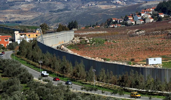 Cars drive next to the wall that separates Lebanon from "Israel" in the southeastern Lebanese village of Kfar Kila, Saturday, Jan. 21, 2023. (AP)