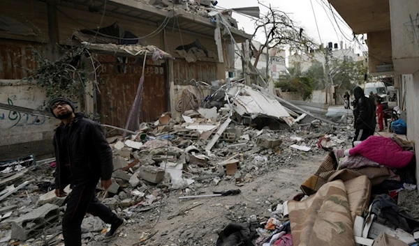 Palestinian citizens look at the residential building of the Khalifa family destroyed in an Israeli strike in Nusseirat refugee camp, central Gaza Strip, Saturday, Dec. 23, 2023 (AP Photo/Adel Hana)