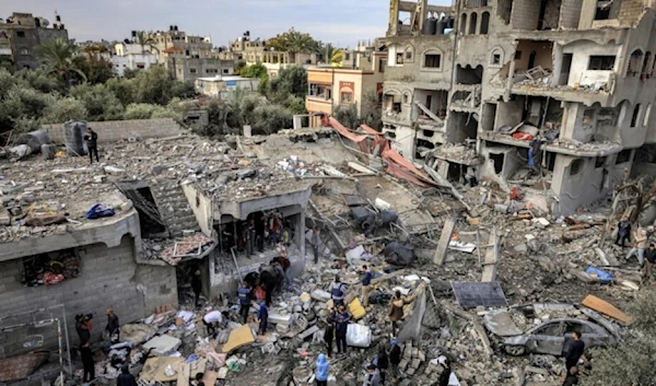 Men recover the body of a victim killed after an Israeli strike at Al-Maghazi refugee camp in central Gaza on December 25, 2023. (AFP)