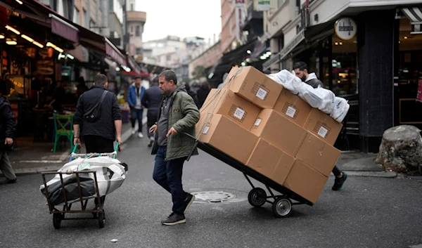 Two men pull trollies with goods in a street market in a commercial district in Istanbul, Turkey, Thursday, Dec. 21, 2023. (AP)