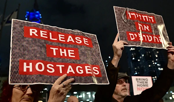 Protesters in 'Tel Aviv' lift placards during a rally for supporters and relatives of Israeli captives held in Gaza. (AFP)