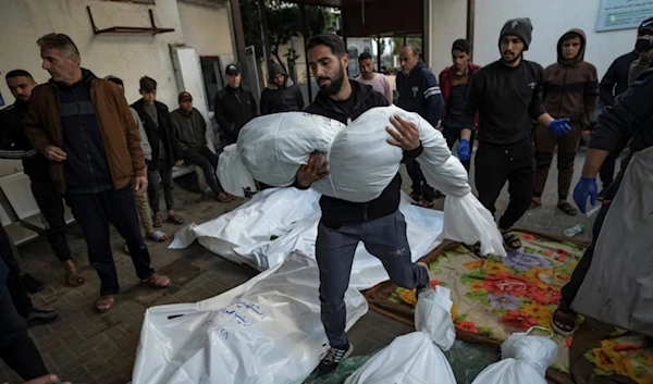 A Palestinian man carries the body of his relative killed in the Israeli bombardment of the Gaza Strip, outside a morgue in Rafah, southern Gaza, Friday, Dec. 29, 2023. (AP Photo/Fatima Shbair)