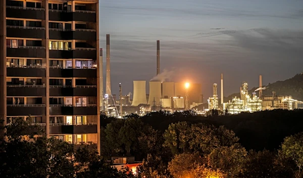 The coal-fired power plant Uniper Scholven and a nearby BP refinery shine in the evening behind illuminated appartments in Gelsenkirchen, Germany, Monday, Oct. 2, 2023 (AP)