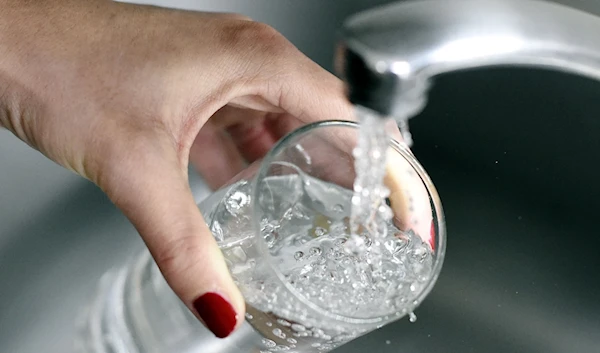 A women drinking water from a tap (AFP via Getty Images)