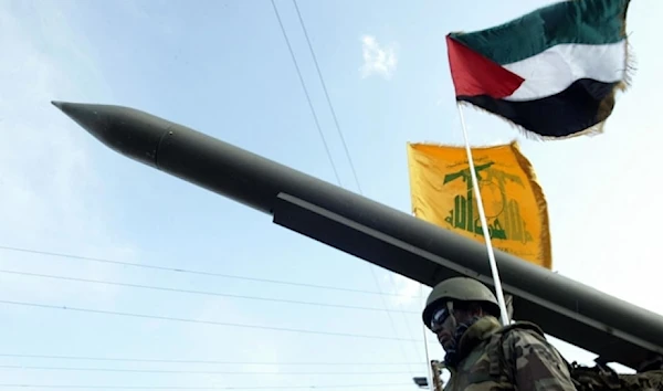 Hezbollah Resistance fighters parade with a missile as the Palestinian (R) and the movement’s (back) flags flutter during an annual parade in the southern city of Nabatieh, Lebanon on January 10, 2009 (AFP)