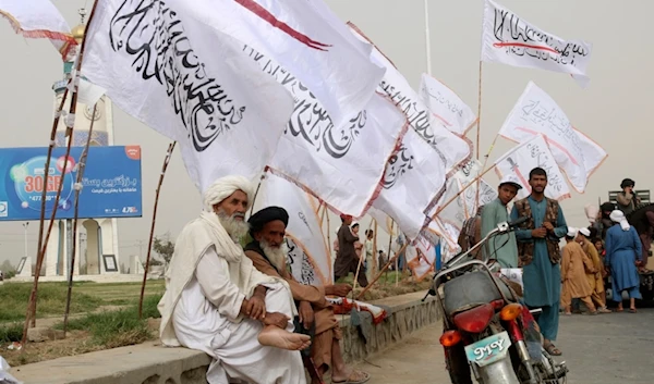 Afghan elderly men sit near to the Taliban flags during a celebration marking the second anniversary of the withdrawal of U.S.-led troops from Afghanistan, Kandahar, Afghanistan, Aug. 15, 2023. (AP)