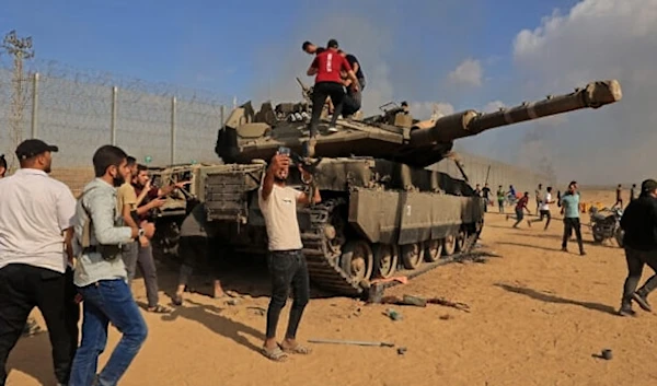 Palestinians take control of an Israeli tank after crossing the occupied Palestinian territory from Khan Younis in the southern Gaza Strip on October 7, 2023. (AFP)