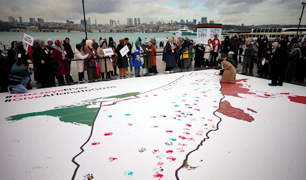 Protesters make hand prints on a map of Palestine during a protest in support of Palestinians marking the World Children's Day, in Istanbul, Monday, Nov. 20, 2023 (AP Photo/Emrah Gurel)