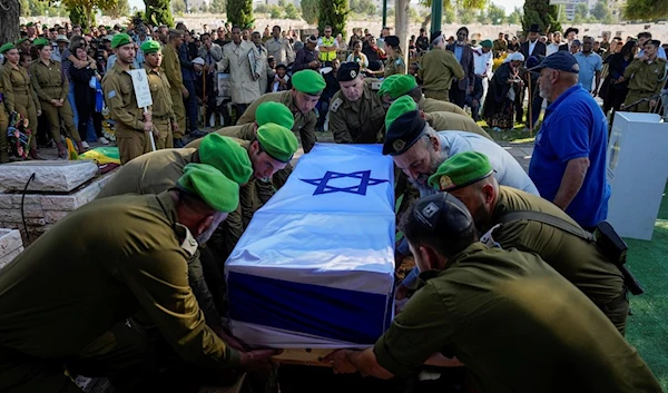 Israeli soldiers lower into the grave the flagged coffin of Staff Sergeant Aschalwu Sama, Sunday, Dec. 3, 2023 (AP)