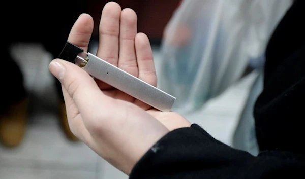 A man displays his Juul electronic cigarette while shopping at a convenience store in Hoboken, NJ, December 20, 2018 (AP)