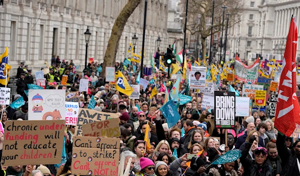 Thousands of demonstrators wave banners as they stand near Downing Street in Westminster in London, Wednesday, Feb. 1, 2023 (AP Photo/Kirsty Wigglesworth)