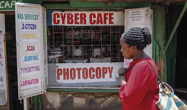 A pedestrian walks oast an internet cafe in the low-income Kiberia neghborhood of Nairobi, Kenya, on Wednesday, Sept. 29, 2021. (AP)