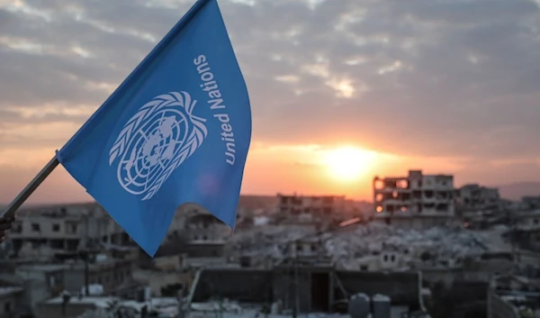 Activists fly an inverted United Nations flag over destroyed buildings in Jindires