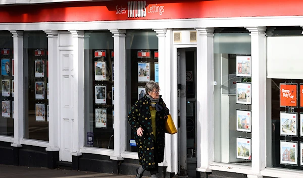 A pedestrian looks at the front window of a real estate agency displaying a selection of properties to buy or rent, in Oxford, on January 30, 2023. (AFP)