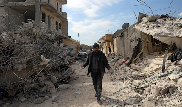 A man walks past collapsed buildings following a devastating earthquake in the town of Jinderis, Aleppo province, Syria, Tuesday, Feb. 14, 2023 (AP Photo/Ghaith Alsayed)