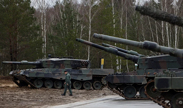 A Polish soldier walks next to the Leopard 2 tanks during a training at a military base and test range in Swietoszow, Poland, Monday, Feb. 13, 2023 (AP Photo/Michal Dyjuk)