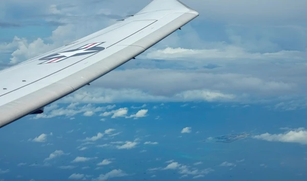 A US P-8A Poseidon reconnaissance plane flies near Chinese structures and buildings on the Fiery Cross Reef at the Spratlys group of islands in the South China Sea seen on March 20, 2022 (AP Photo)