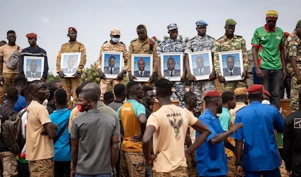 Mourners hold photos of soldiers that were killed by jihadists October 2022. (AFP)