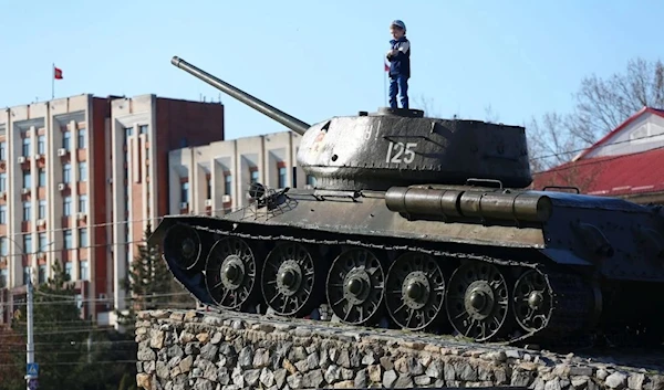 A child stands on the T-34 Soviet tank set as a monument in the center of Tiraspol, capital of self-proclaimed Moldovan Republic of Transnistria on April 3, 2017. (AFP)