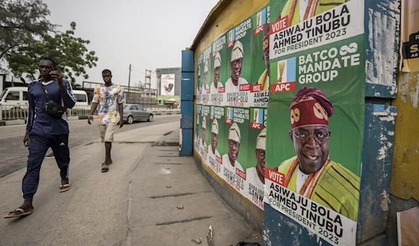 Pedestrians walk past campaign posters for presidential candidate Bola Tinubu of the All Progressives Congress in Lagos, Nigeria Thursday, Feb. 23, 2023. (AP Photo/Ben Curtis)