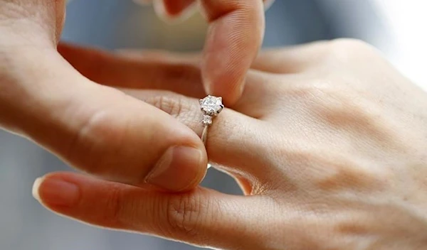 A man puts an engagement ring on a woman's finger during a photo opportunity at a jewelers store in Tokyo June 2, 2009. (Reuters)