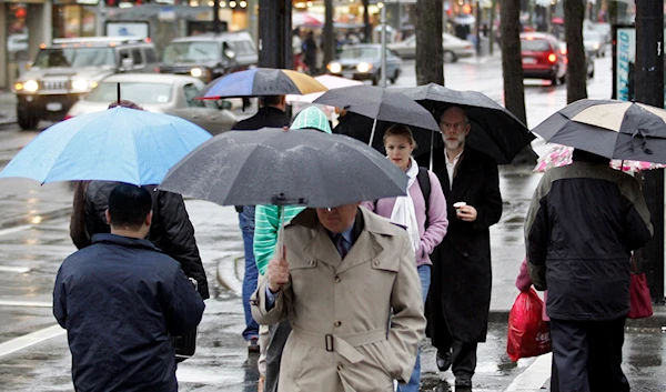 Pedestrians take cover under their umbrellas while crossing a street in Vancouver, B.C., Thursday, Jan. 12, 2006. (AP)