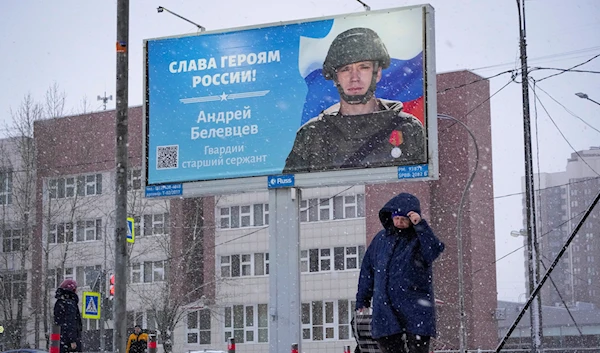 A woman walks past a billboard with a portrait of a Russian soldier awarded for action in Ukraine and the words "Glory to the heroes of Russia" in St. Petersburg, Russia, Tuesday, Jan. 3, 2023 (AP Photo/Dmitri Lovetsky)