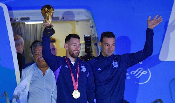 Argentina's Lionel Messi holds the FIFA World Cup trophy as he deplanes, with coach Lionel Scaloni, in Buenos Aires, Argentina, Tuesday, Dec. 20, 2022 (AP Photo/Gustavo Garello)