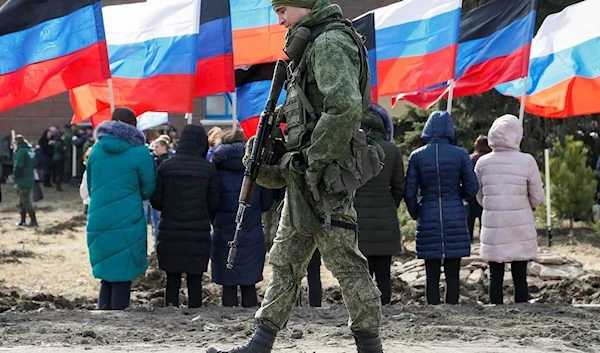 DPR soldier in the Donbas region walking infront of a crowd waving the flags of the Russian Federation (Reuters) and the  Donetsk People's Republic,