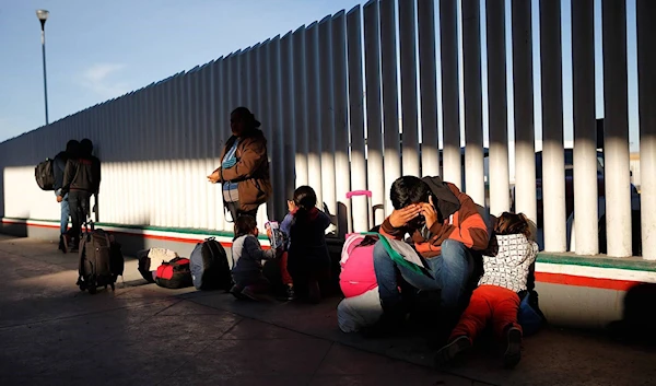 A migrant sits with his children as they wait to hear if their number is called to apply for asylum in the United States, at the border on January 25, 2019, in Tijuana, Mexico. (AP Photo)