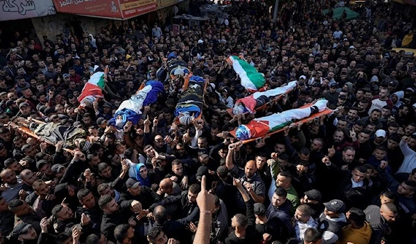 Mourners carry the bodies of eight Palestinian martyrs during a joint funeral, Jan.26, 2023 (AP)