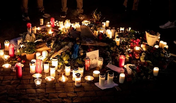 People lay flowers and candles near a crime scene in the Hammarby Sjostad district in Stockholm on October 22, 2021. (AFP)