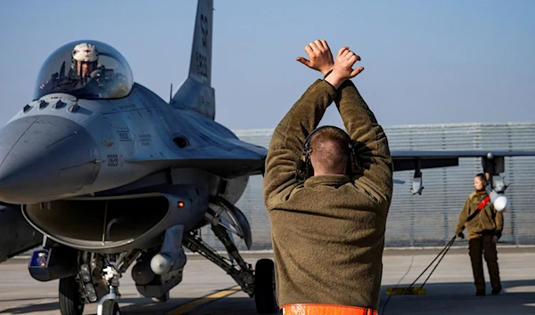 A US Air Force member marshalling an F-16 fighter jet in Romania in February 2022 (Reuters)