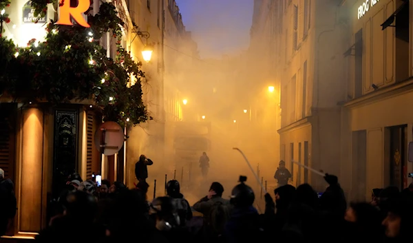 Youths face riot police officers, background, during scuffles as part of a demonstration against plans to push back France's retirement age, February 7, 2023 in Paris, France (AP Photo)