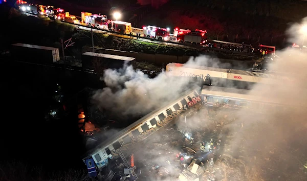 Smoke rises from trains as firefighters and rescuers operate after a collision near Larissa city, Greece, early Wednesday, March 1, 2023 (AP).