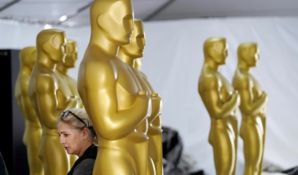 Antje Menikheim, left, lead scenic painter for Sunday's 95th Academy Awards, inspects Oscar statues in preparation for the event, Wednesday, March 8, 2023, near the Dolby Theatre in Los Angeles. (AP)